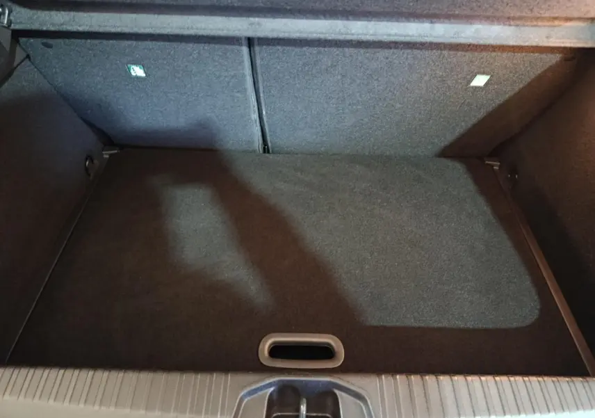 Vue plongeante sur le coffre spacieux et vide de la Renault Clio gris clair, montrant le revêtement intérieur noir.