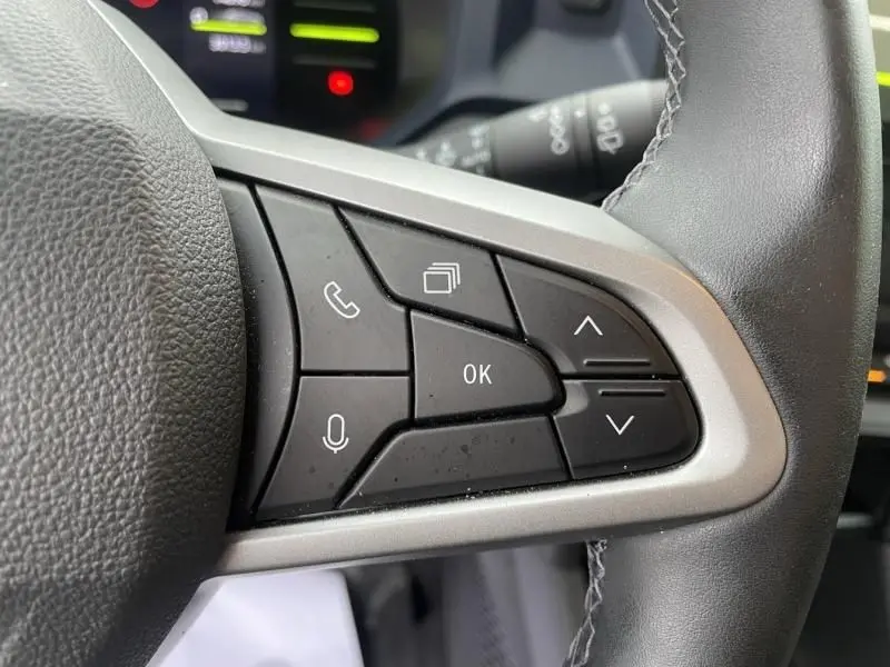 Gros plan sur les commandes multifonctions côté droit du volant du Dacia Duster 2025 gris schiste, version hybride.