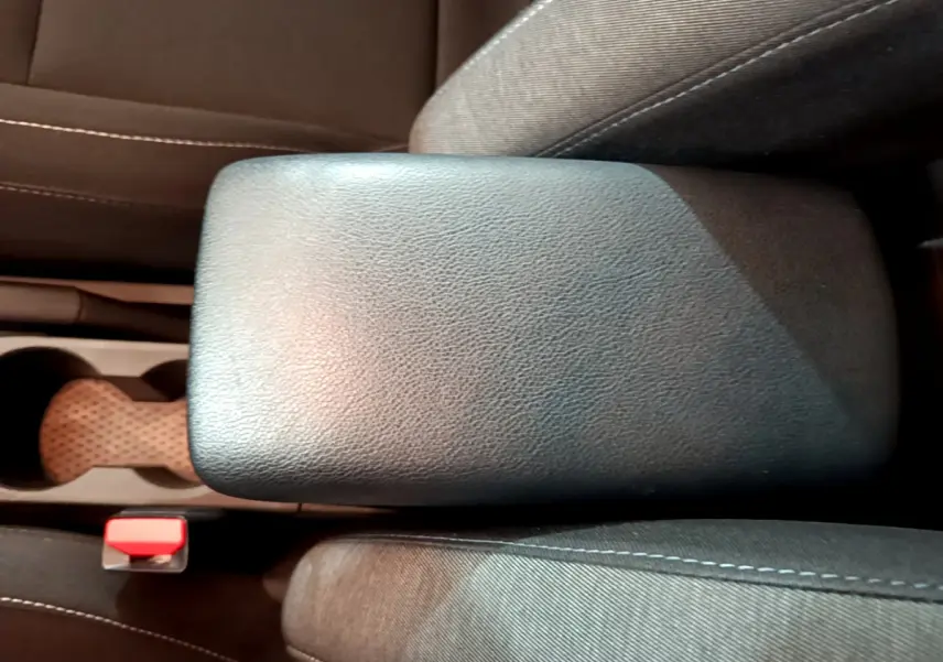 Vue rapprochée de l'accoudoir central noir et des sièges en tissu gris du Renault Captur Business 2020.