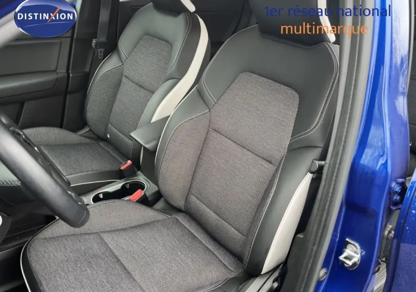 Vue intérieure côté conducteur du Renault Captur bleu iron metal, mettant en valeur les sièges tissu et cuir noir avec surpiqûres blanches.