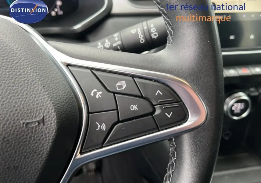 Gros plan sur les commandes au volant à droite du Renault Captur hybride rechargeable, cuir noir avec surpiqûres blanches.