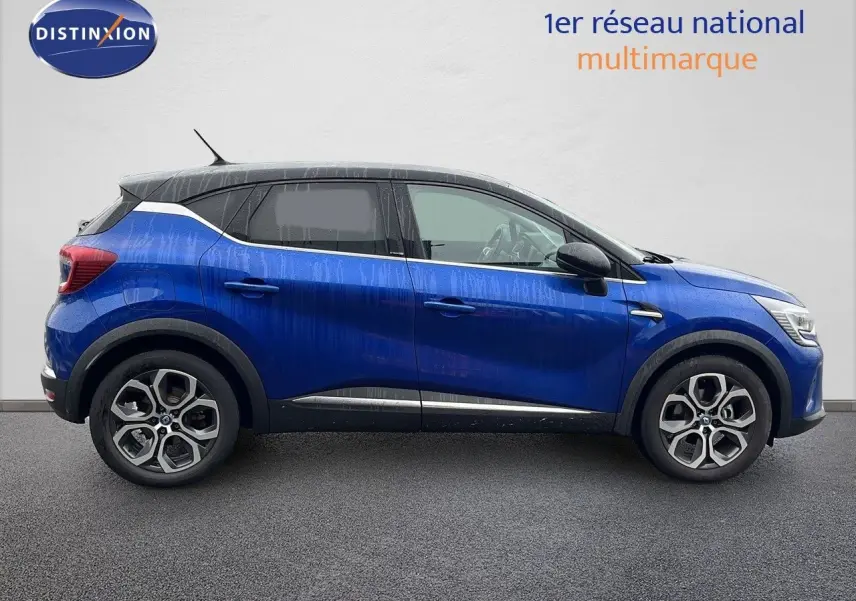 Profil droit d'un Renault Captur 1.6 E-Tech hybride rechargeable bleu iron metal avec toit noir, jantes alliage bi-ton.