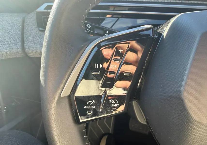 Gros plan sur les commandes gauche du volant du Peugeot 3008 Hybrid gris, avec boutons de régulateur et limiteur de vitesse.