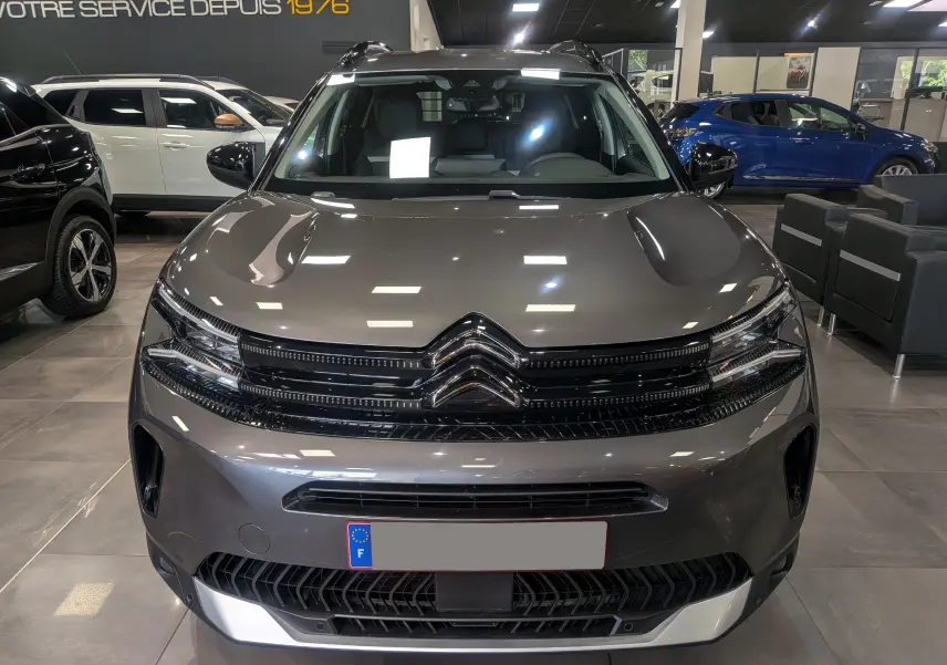Vue frontale d'un Citroën C5 Aircross Hybride gris Platinium, soulignant la calandre et les phares LED au showroom.