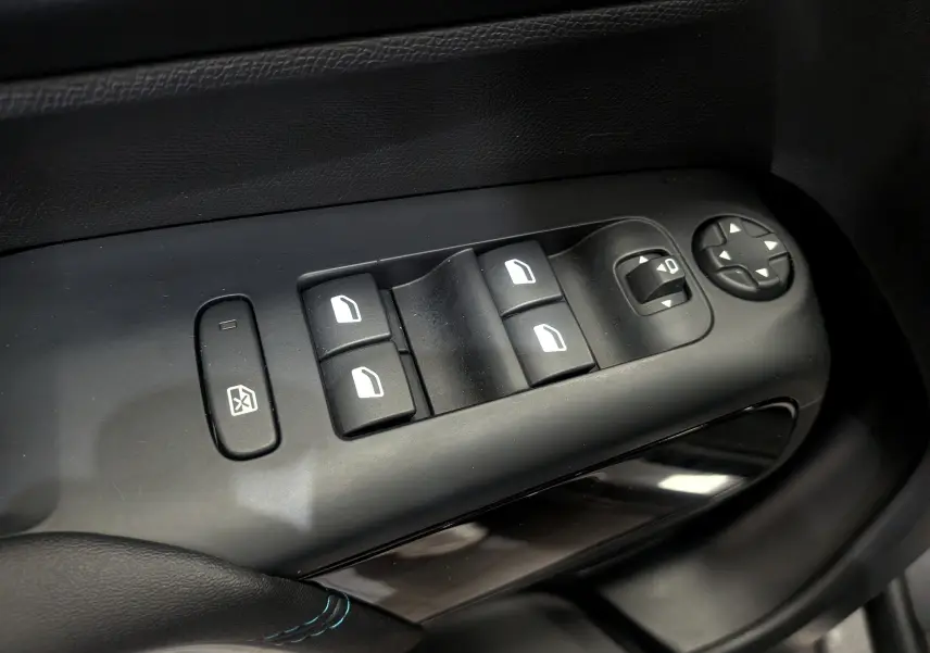 Gros plan sur les commandes de lève-vitres et rétroviseurs côté gauche du Citroën C5 Aircross gris Platinium 2025.