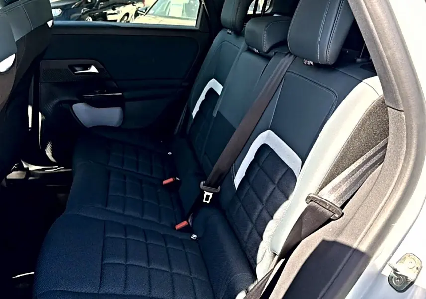 Vue intérieure arrière côté droit du Citroën C5 Aircross 2026, sièges noirs avec inserts gris et ceinture attachée.