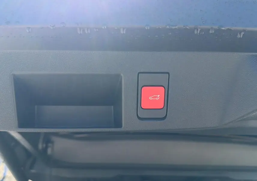 Bouton rouge d'ouverture électrique du hayon sur la partie intérieure du coffre d'un Citroën C5 Aircross blanc et noir.