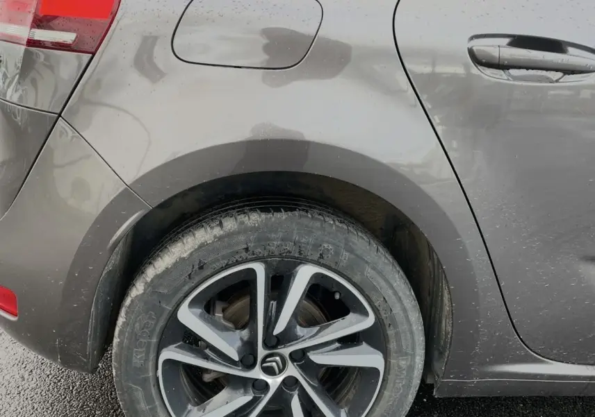 Gros plan sur la roue arrière gauche et la portière marron d'une Citroën C4 Picasso avec jante alu au design moderne.