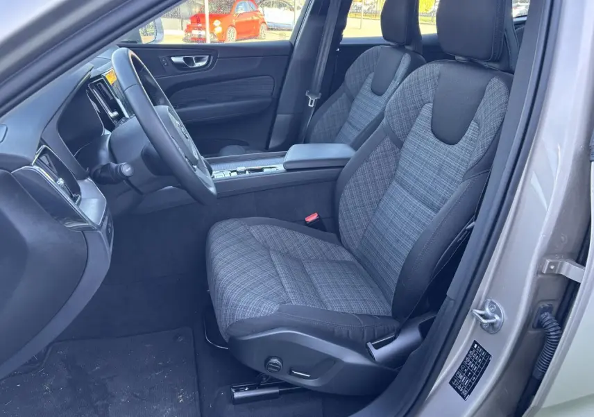 Intérieur avant côté conducteur d’un Volvo XC60 argent crépuscule, sièges tissu à motifs et volant simili-cuir.
