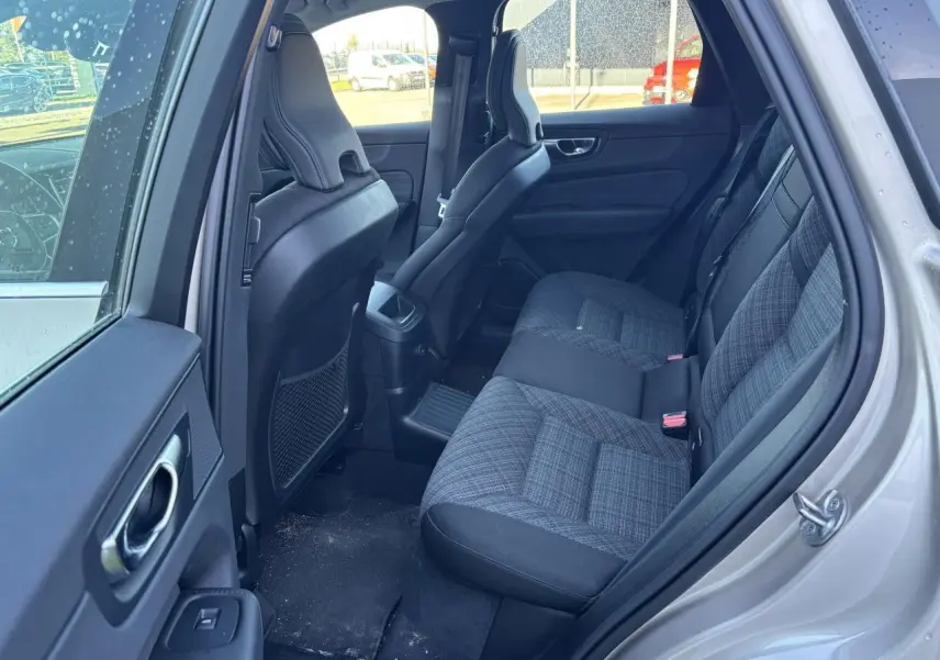 Vue intérieure côté arrière droit du Volvo XC60 2024 argent crépuscule, montrant les sièges arrière en tissu gris à motifs.
