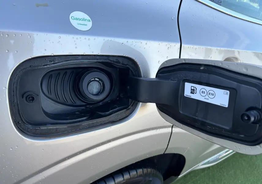 Détail de la trappe à carburant ouverte côté gauche d’un Volvo XC60 argent crépuscule métal avec gouttes d’eau.