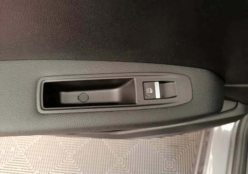 Bouton de lève-vitre électrique sur la porte côté droit du Renault Captur gris foncé 2025 en vue rapprochée.