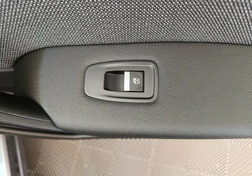 Bouton de commande de lève-vitre automatique sur la portière intérieure noire d'un Renault Captur gris foncé 2025.