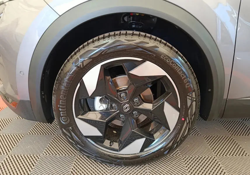 Gros plan sur la roue avant droite du Renault Captur gris foncé, mettant en valeur la jante noire au design étoilé.