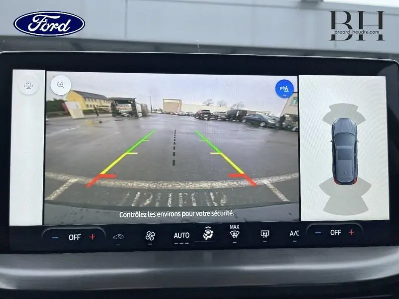 Vue écran multimédia montrant la caméra de recul et l'affichage 360° du Ford Focus SW noir Agate métallisé en stationnement.