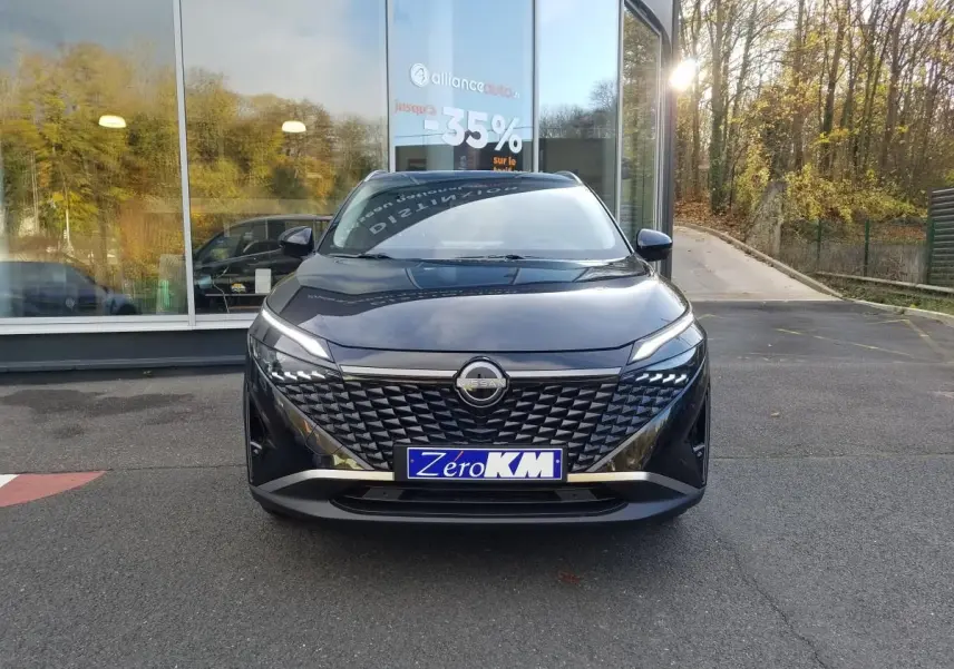 Vue avant d'un Nissan Qashqai noir 2025 avec calandre texturée et phares LED fins, stationné devant une vitrine.