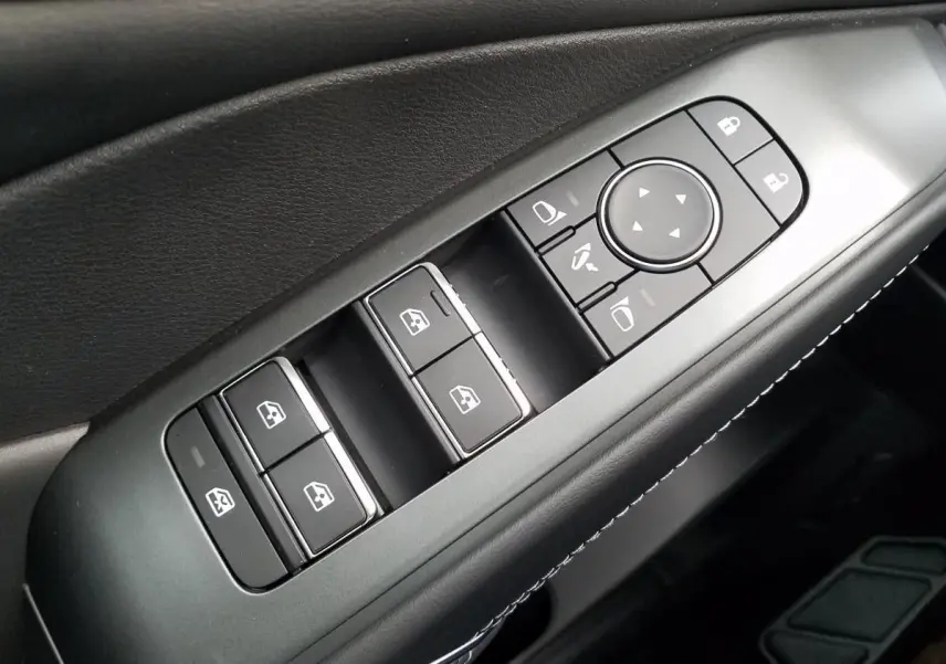 Gros plan sur les commandes de lève-vitres et rétroviseurs côté conducteur du Nissan Qashqai noir 2025.