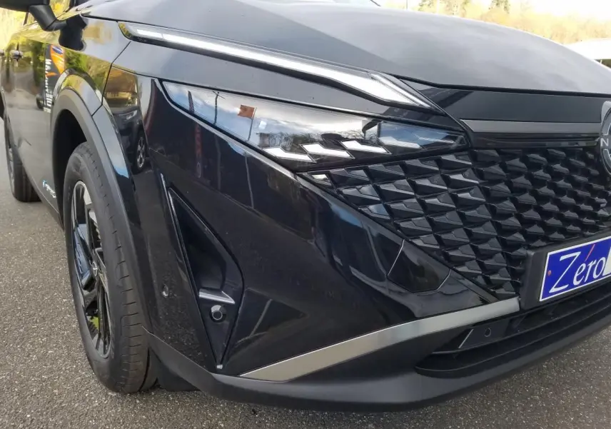 Vue avant gauche rapprochée du Nissan Qashqai noir 2025 avec calandre texturée et phares LED distinctifs.
