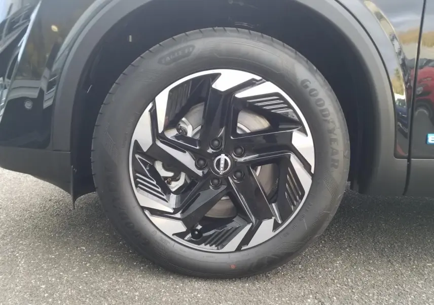Gros plan sur la roue avant droite du Nissan Qashqai noire avec jante alliage 18 pouces au design moderne.
