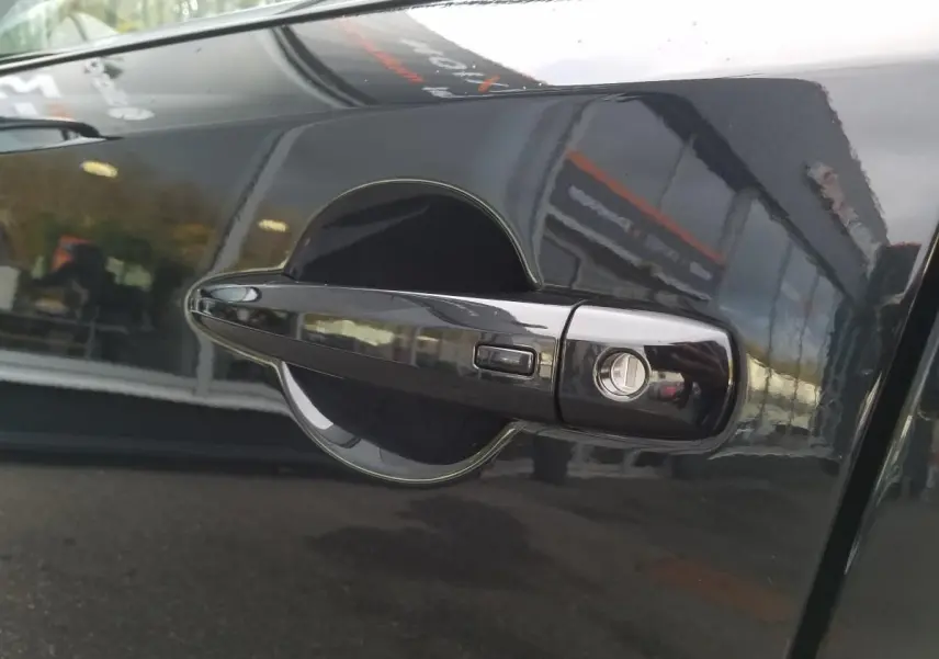 Poignée de porte avant droite noire du Nissan Qashqai 2025 avec serrure et bouton de déverrouillage.