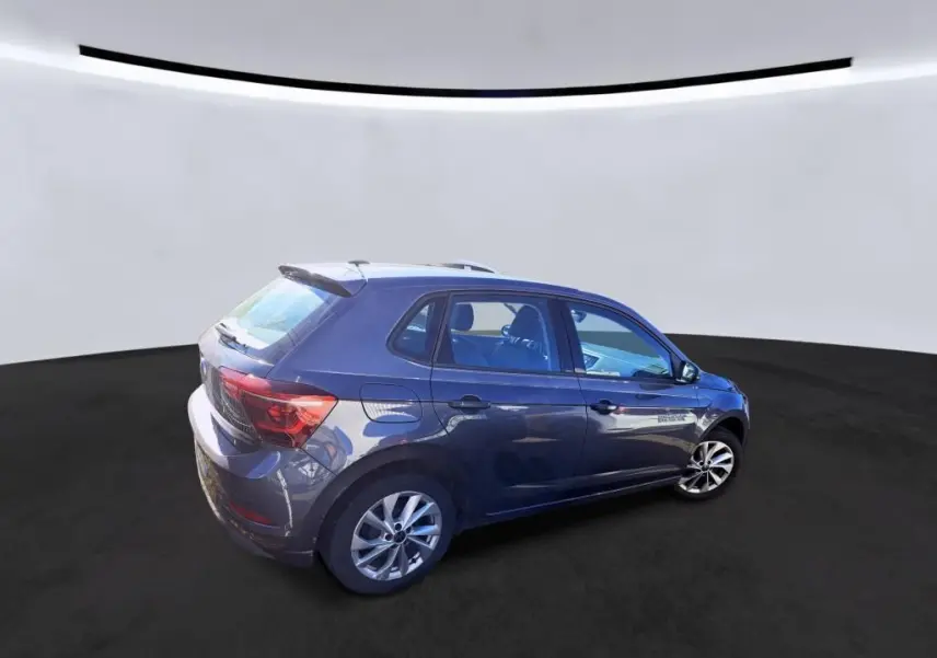 Vue 3/4 arrière droite d'une Volkswagen Polo gris métallisé avec jantes alliage et déflecteur de toit intégré.