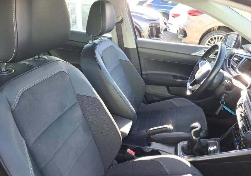 Vue intérieure côté droit de la Volkswagen Polo 1.0 TSI 95 Style 2022, sièges noirs avec surpiqûres blanches et levier de vitesses manuel.