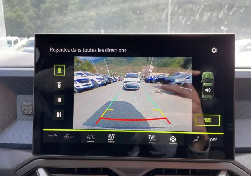 Écran de caméra multiview affichant une vue arrière avec un Dacia Duster vert cèdre en stationnement.