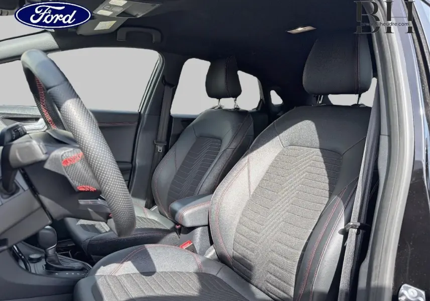 Vue intérieure côté conducteur du Ford Puma 2023 noir Agate, sièges tissu et cuir avec surpiqûres rouges et volant sport.
