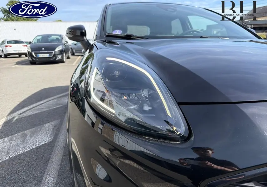 Gros plan sur le phare avant gauche du Ford Puma 2023 noir Agate Métallisée, mettant en valeur son design moderne et lumineux.