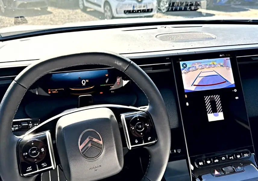 Vue intérieure centrée sur le volant noir et l'écran tactile affichant la caméra de recul du Citroën C5 Aircross blanc.