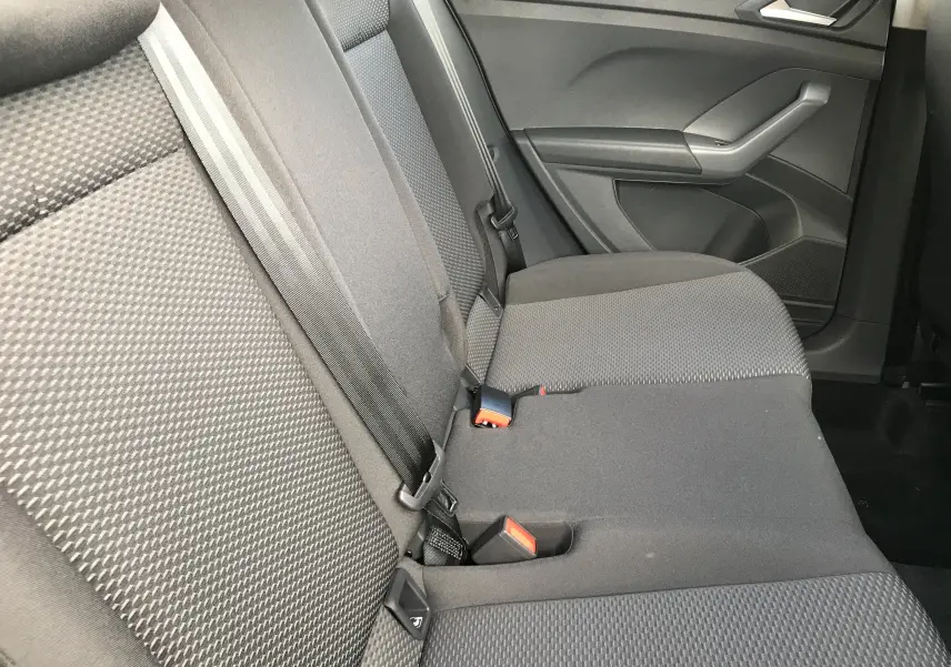 Vue latérale intérieure des sièges arrière en tissu noir du Volkswagen T-Cross 2020, avec ceintures de sécurité visibles.