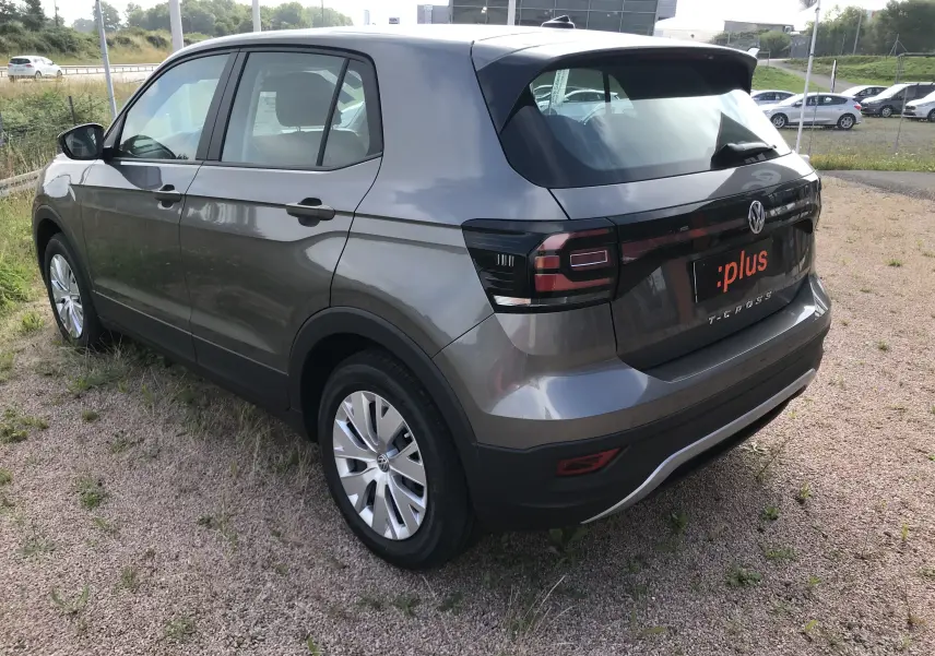 Vue 3/4 arrière droite du Volkswagen T-Cross gris Limestone 2020 avec feux arrière noirs et jantes argentées.