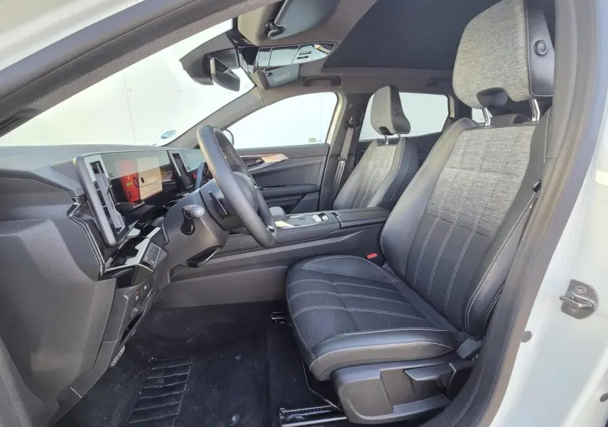 Vue intérieure côté conducteur du Renault Austral 2025 blanc nacré, sièges tissu et cuir noir, toit panoramique visible.