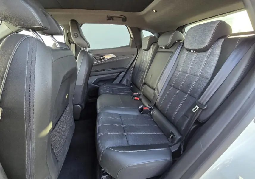 Vue latérale intérieure montrant la banquette arrière en cuir noir et tissu gris du Renault Austral 2025 blanc nacré.