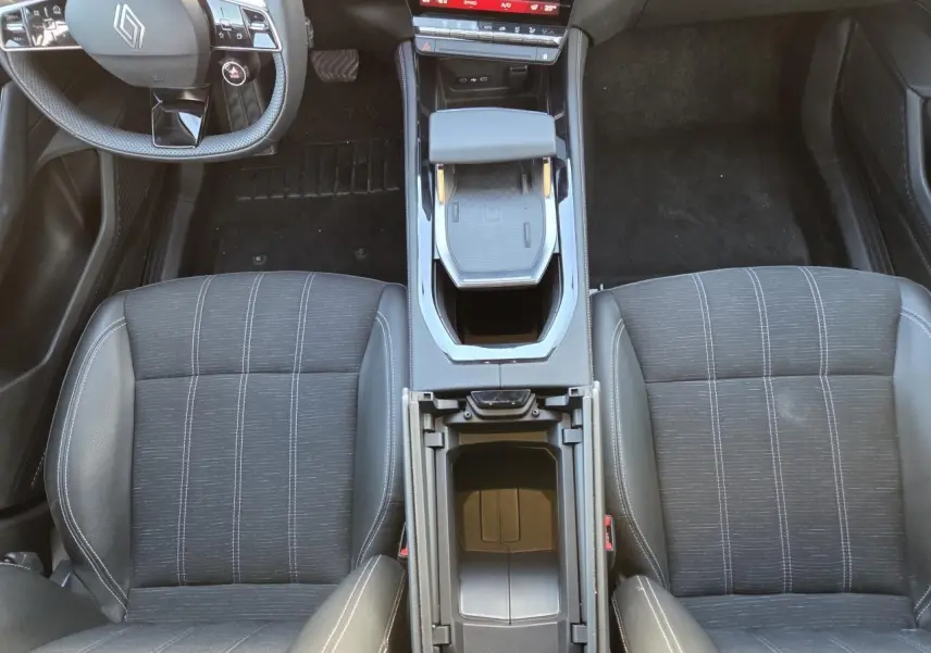 Vue intérieure plongeante sur les sièges avant noirs et la console centrale ouverte du Renault Austral E-Tech 2025.