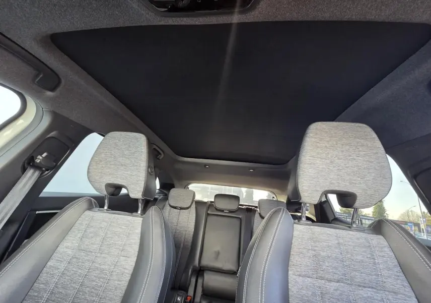 Vue intérieure du Renault Austral 2025 montrant les sièges avant gris clair avec coutures blanches et toit panoramique noir étoilé.