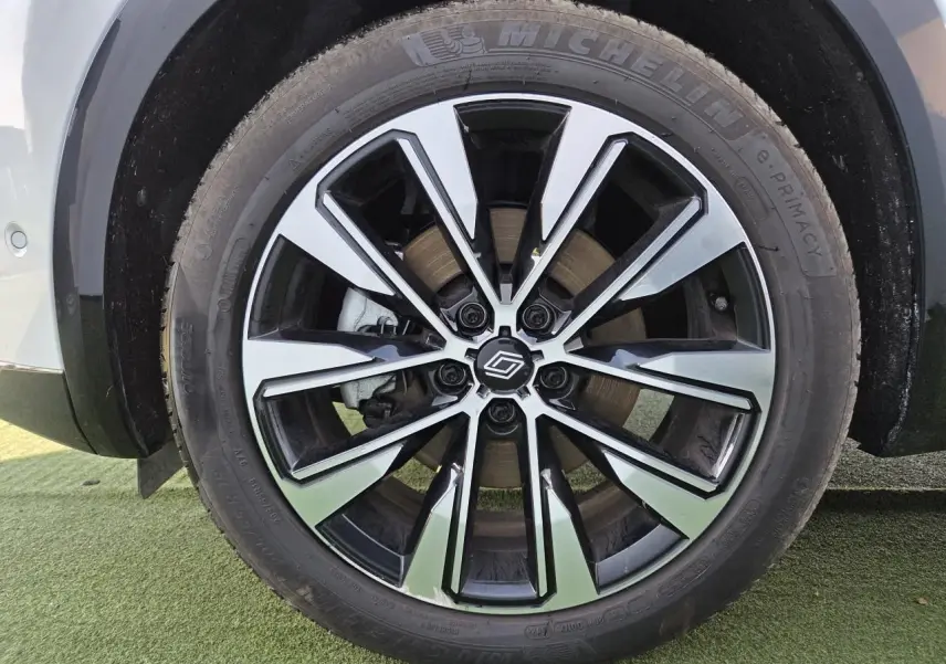 Gros plan sur la jante alliage noire et argentée du côté gauche d'un Renault Austral blanc nacré.