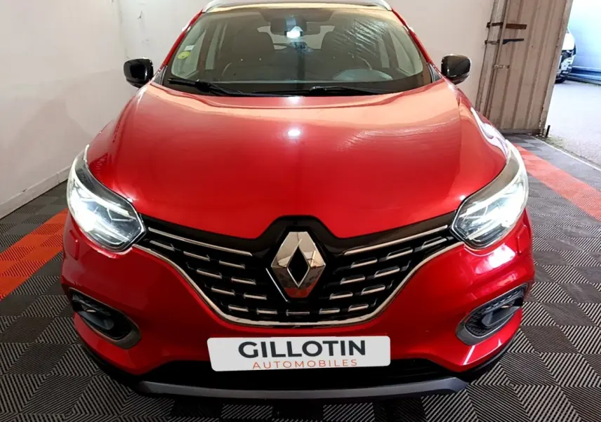 Vue avant d’un Renault Kadjar rouge avec calandre chromée et phares allumés dans un garage.