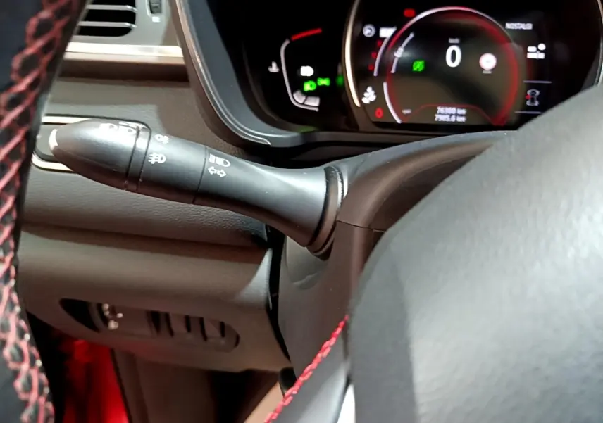 Gros plan intérieur sur le volant noir avec surpiqûres rouges et le combiné d'instruments numérique du Renault Kadjar rouge.