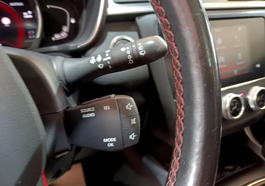 Gros plan sur le volant cuir noir avec surpiqûres rouges et commandes audio du Renault Kadjar rouge, version 2019.