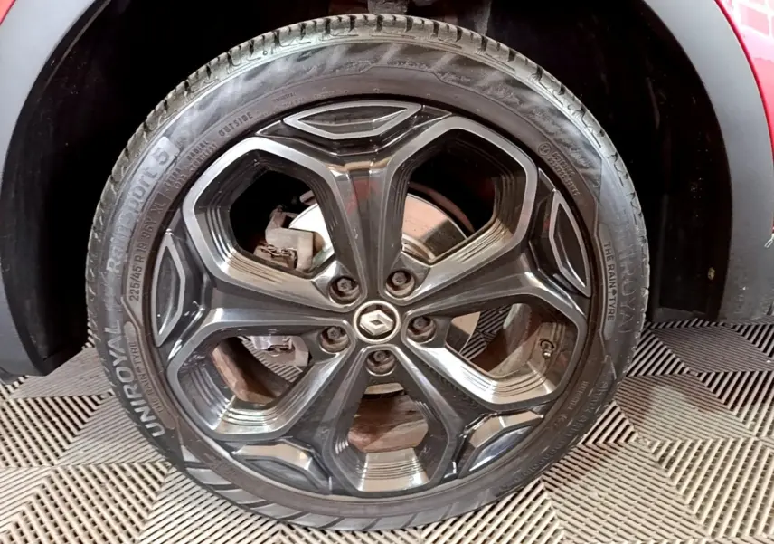 Gros plan sur la roue avant droite du Renault Kadjar rouge, jante alliage noire au design hexagonal.