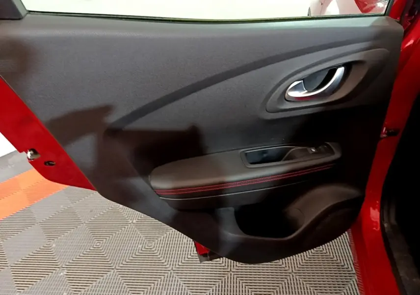 Vue rapprochée de la porte arrière gauche rouge du Renault Kadjar avec accoudoir noir et surpiqûres rouges.