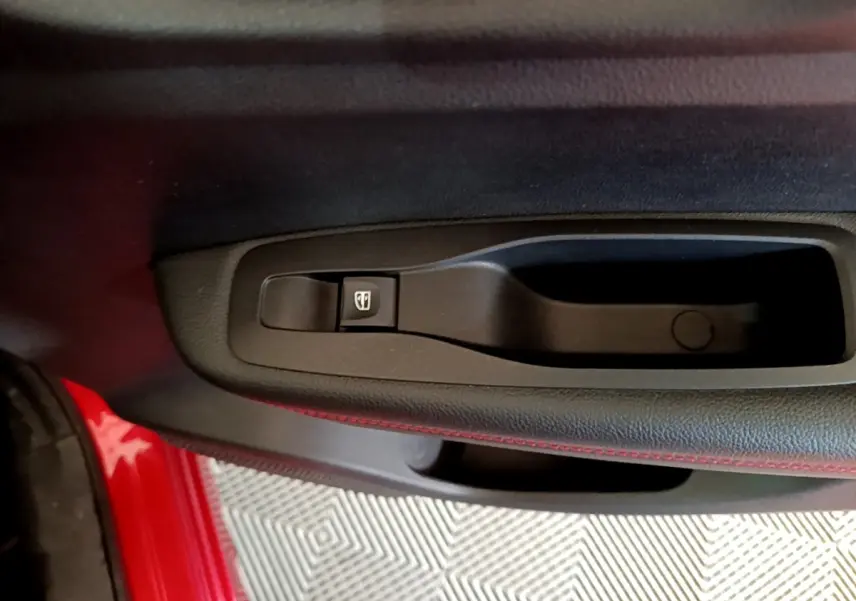 Gros plan sur la commande de lève-vitre côté conducteur du Renault Kadjar rouge, avec surpiqûres rouges visibles.