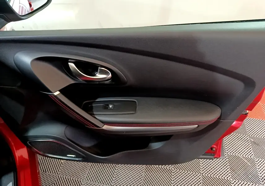 Vue rapprochée de la porte avant gauche rouge du Renault Kadjar 2019 avec poignée chrome et surpiqûres rouges.