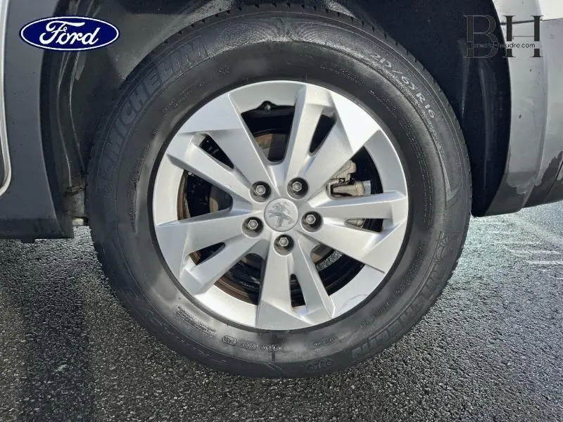 Gros plan sur la roue avant droite du Peugeot Rifter blanc avec jante alliage et logo Peugeot central.