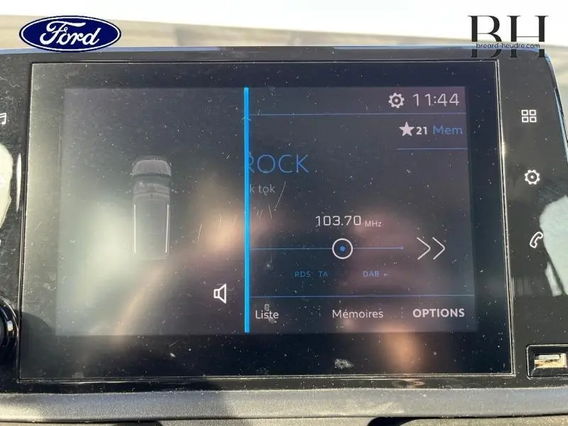 Écran tactile central du tableau de bord affichant la radio FM à 103,7 MHz dans un véhicule Ford.