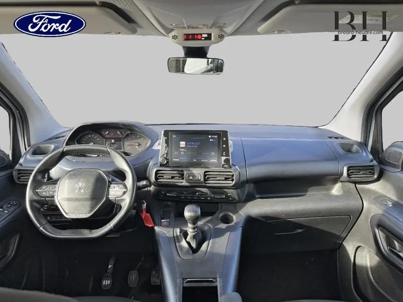 Vue intérieure avant du Peugeot Rifter 2020 blanc, montrant le tableau de bord avec écran tactile et volant cuir.