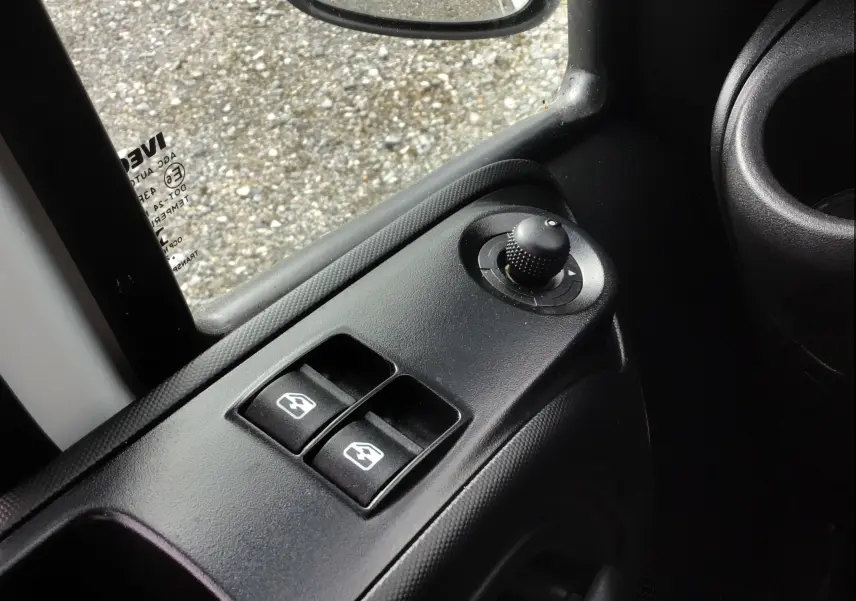 Gros plan sur les commandes électriques de vitres et rétroviseurs côté conducteur du camion blanc Iveco Daily Chassis Cabine 2022.