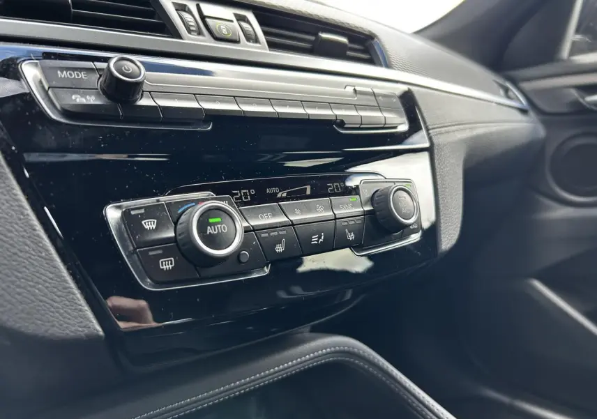 Détail du tableau de bord noir brillant avec commandes de climatisation automatique sur BMW X2 F39 2021.