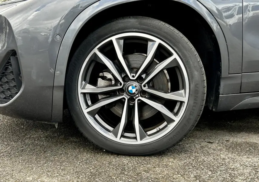 Gros plan sur la jante avant droite bicolore 19 pouces style 919 M d'un BMW X2 gris Mineral avec badge M sur l'aile.